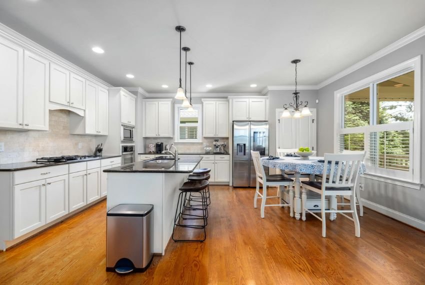 wooden floor kitchen with white cabinets and lightning.