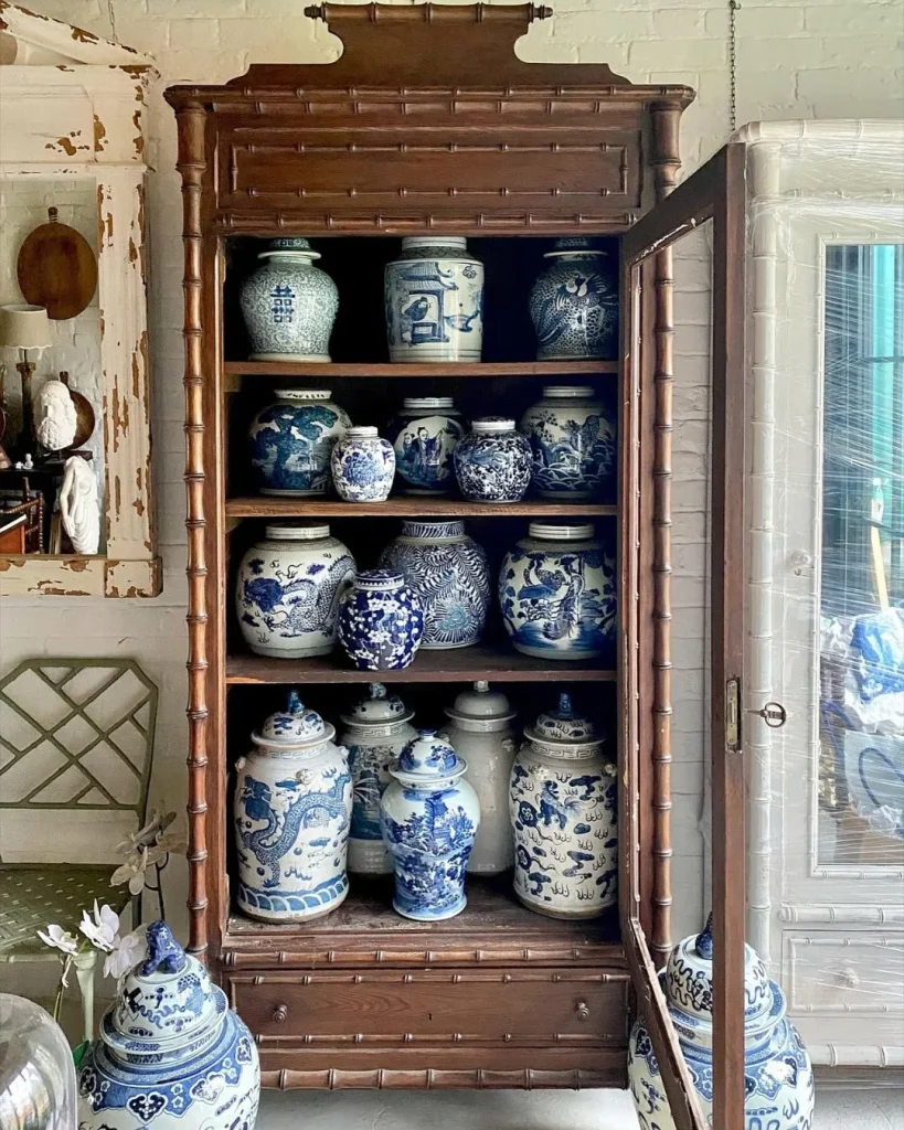 Bookcase with blue and white chinoiserie wallpaper and porcelain ginger jars