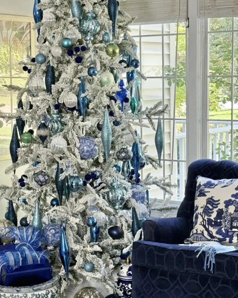 White flocked tree with emerald, ruby and sapphire ornaments