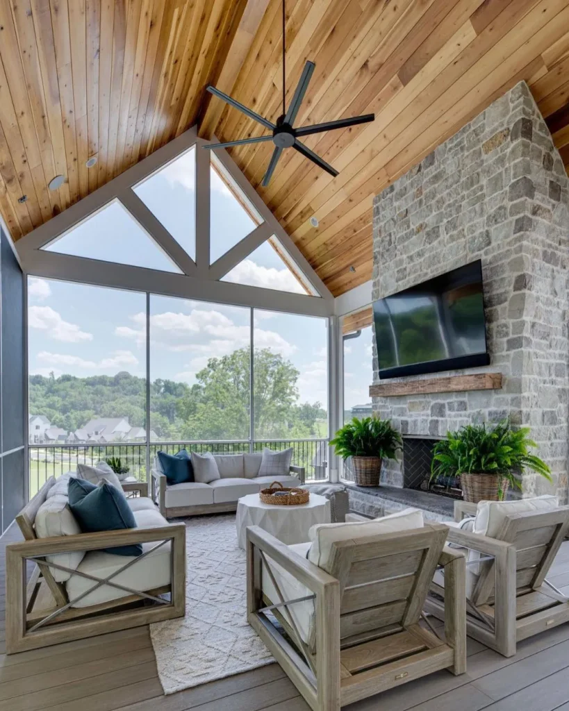 a corner of a screened porch with a stacked stone electric fireplace