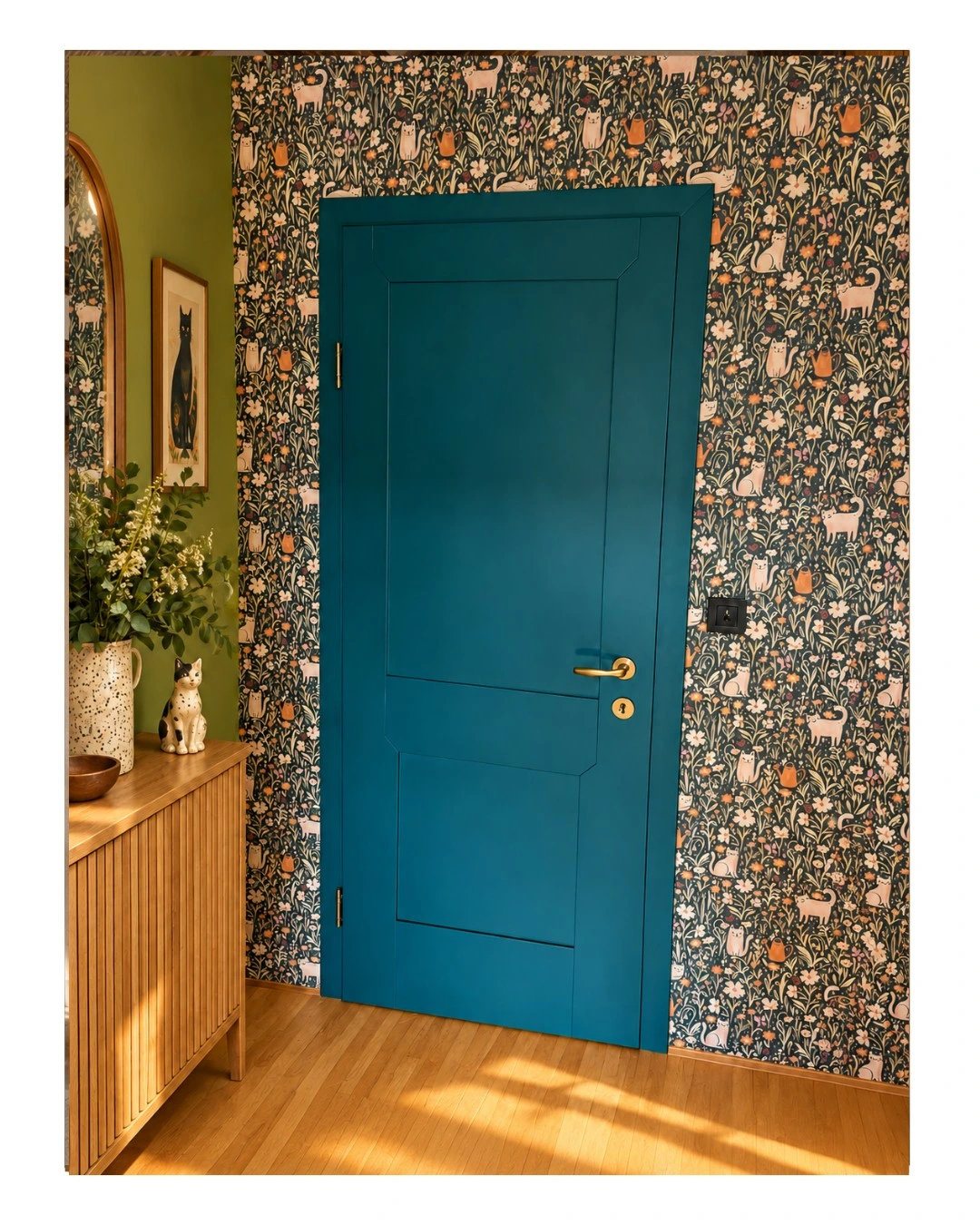 Deep teal paneled door with brass handle against patterned wallpaper