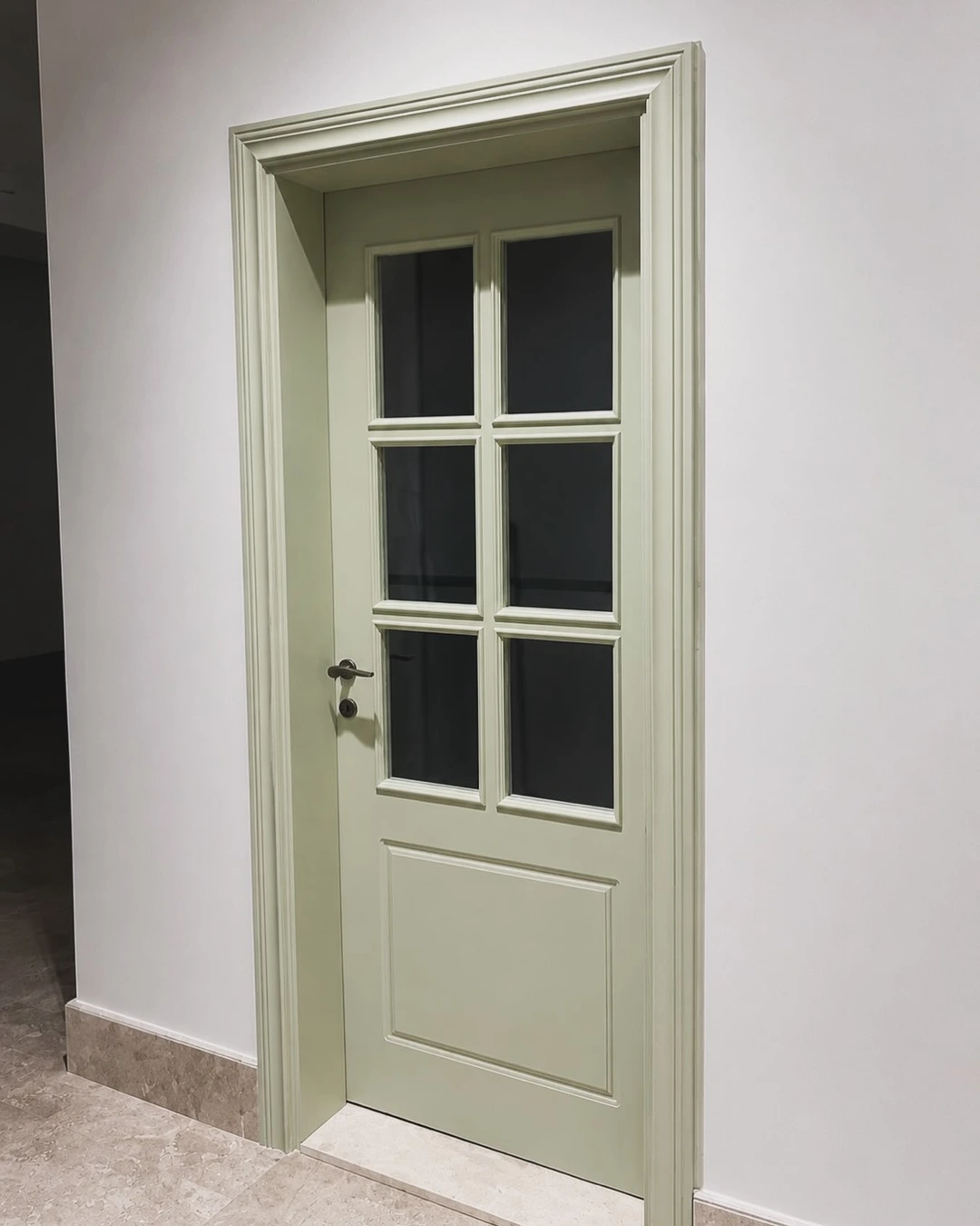 Soft sage green door with six glass panes and matching sage frame
