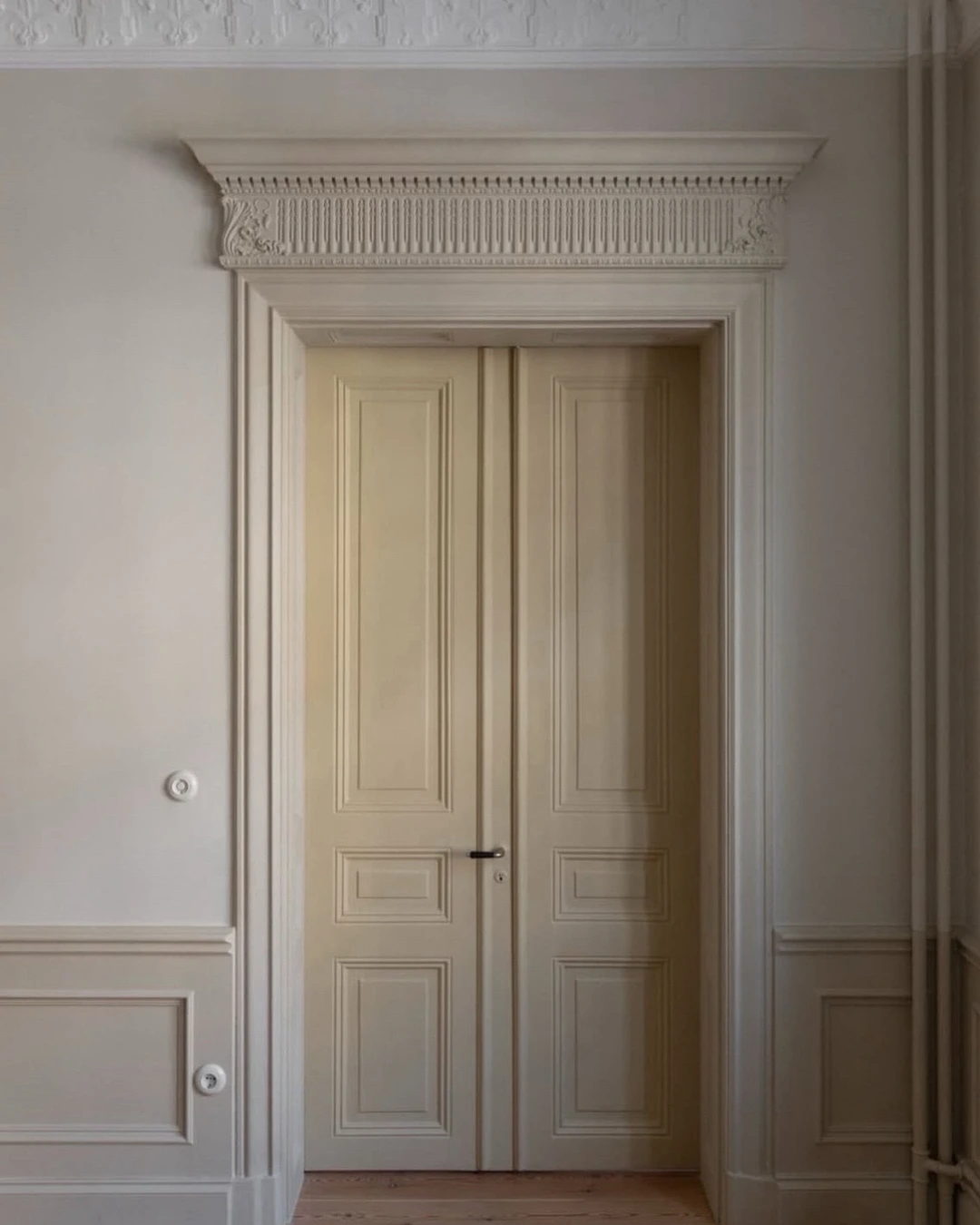Cream paneled double doors in an ornate classical frame