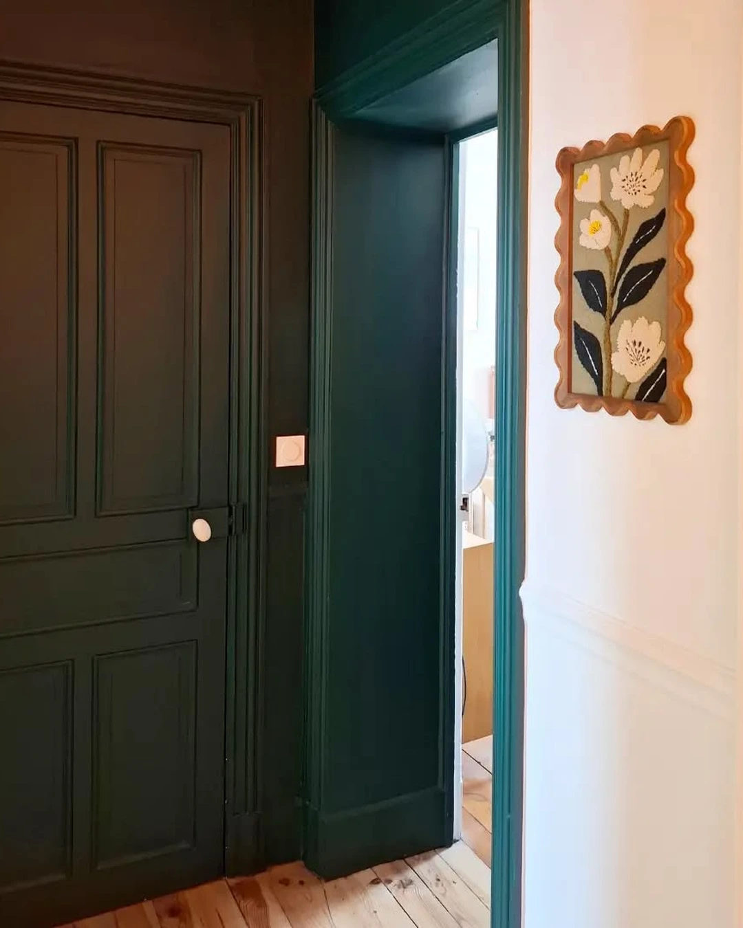 Deep forest green paneled door with matching green trim and an open doorway beside it