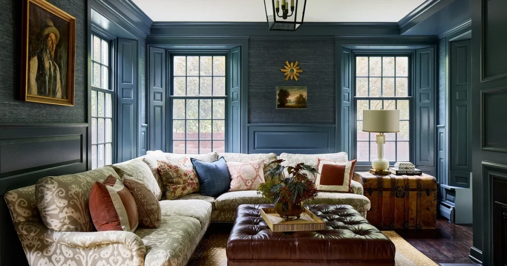 Living room with blue-gray paneled walls, textured grasscloth panels, patterned sectional and leather ottoman