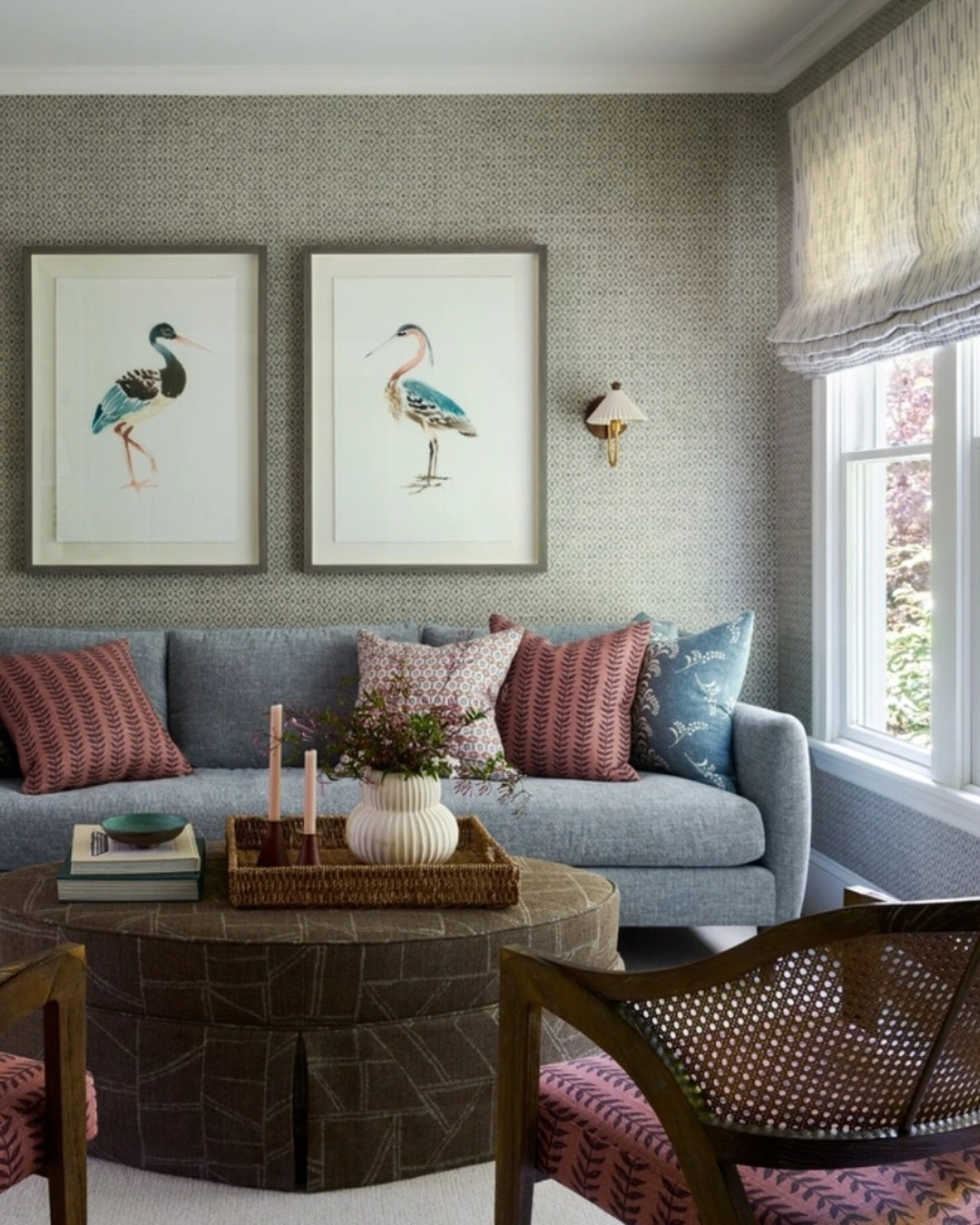 Living room with patterned grasscloth wall behind a blue-gray sofa, bird artwork and sconces