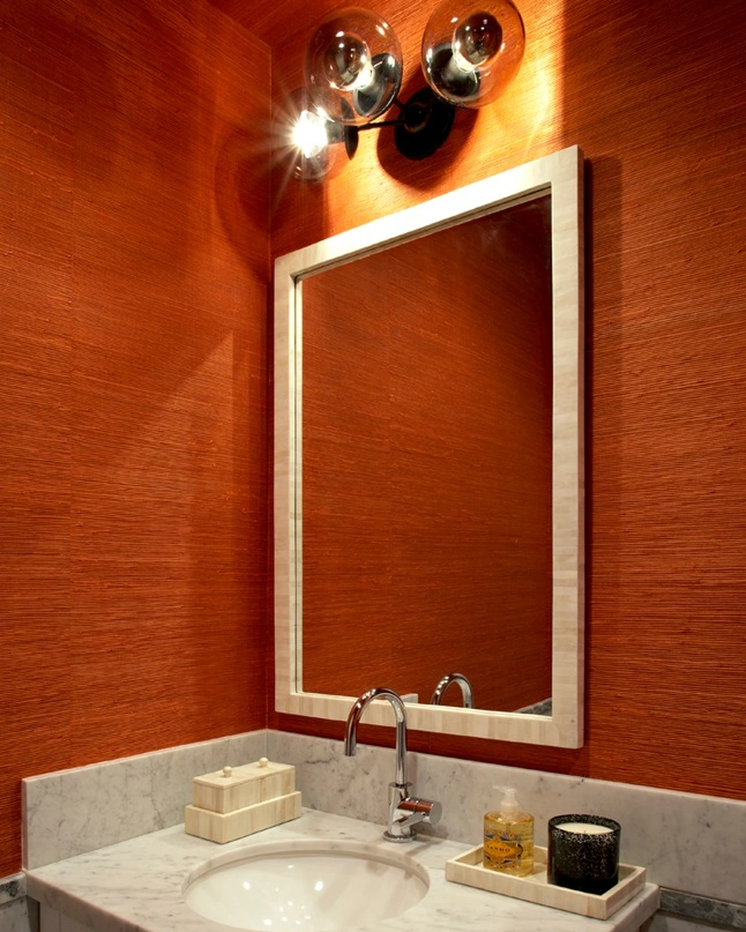 Powder room with rust grasscloth walls and ceiling, marble vanity and framed mirror