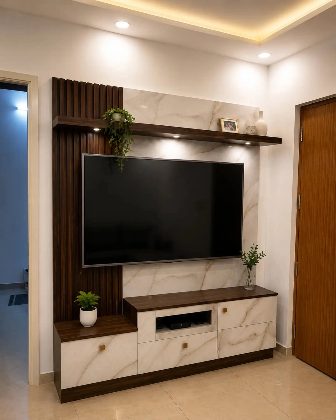 TV wall with dark wood fluting beside a white marble-vein panel, floating shelf and marble-front console