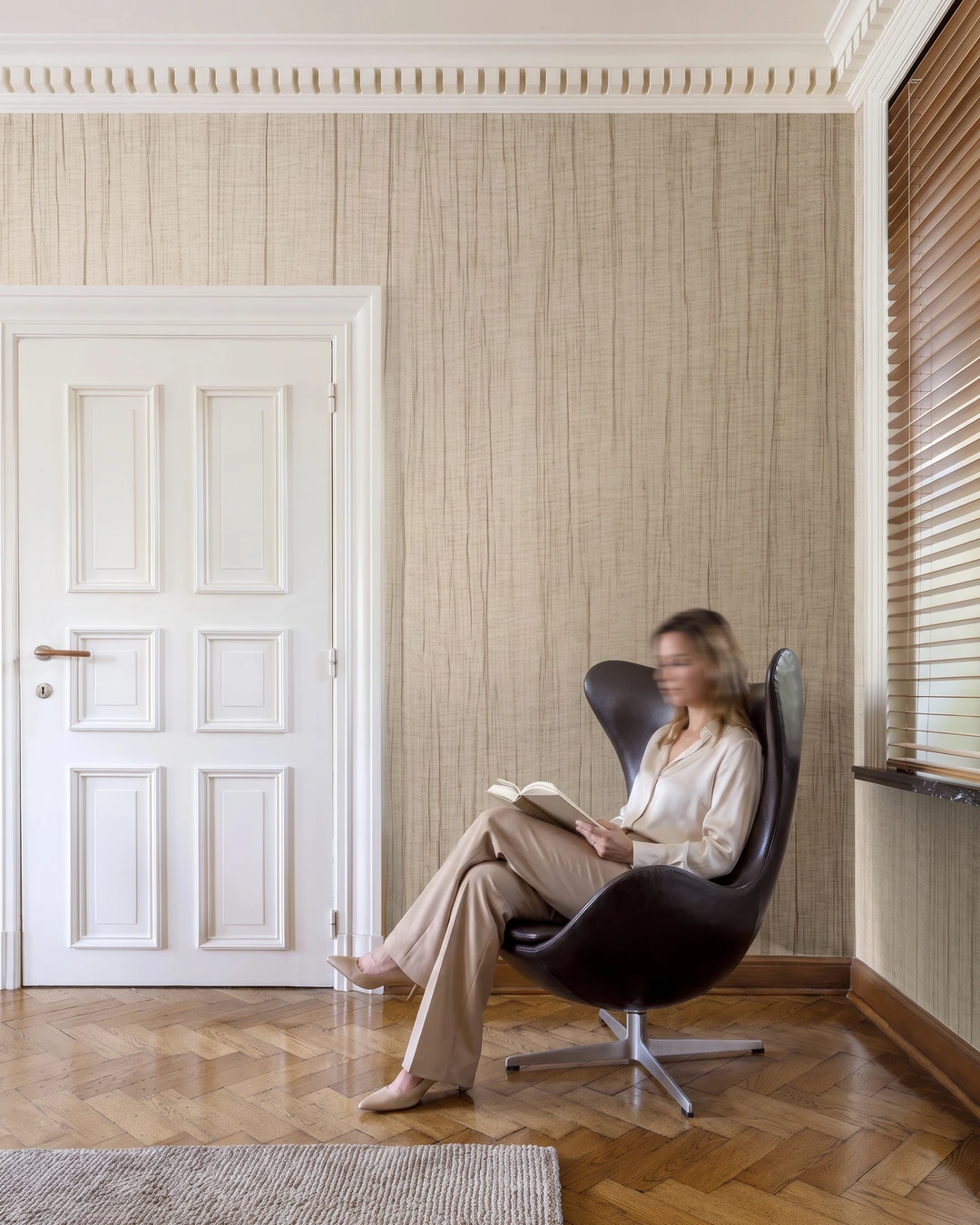 Beige vertically textured linen wallcovering beside herringbone parquet and a white paneled door