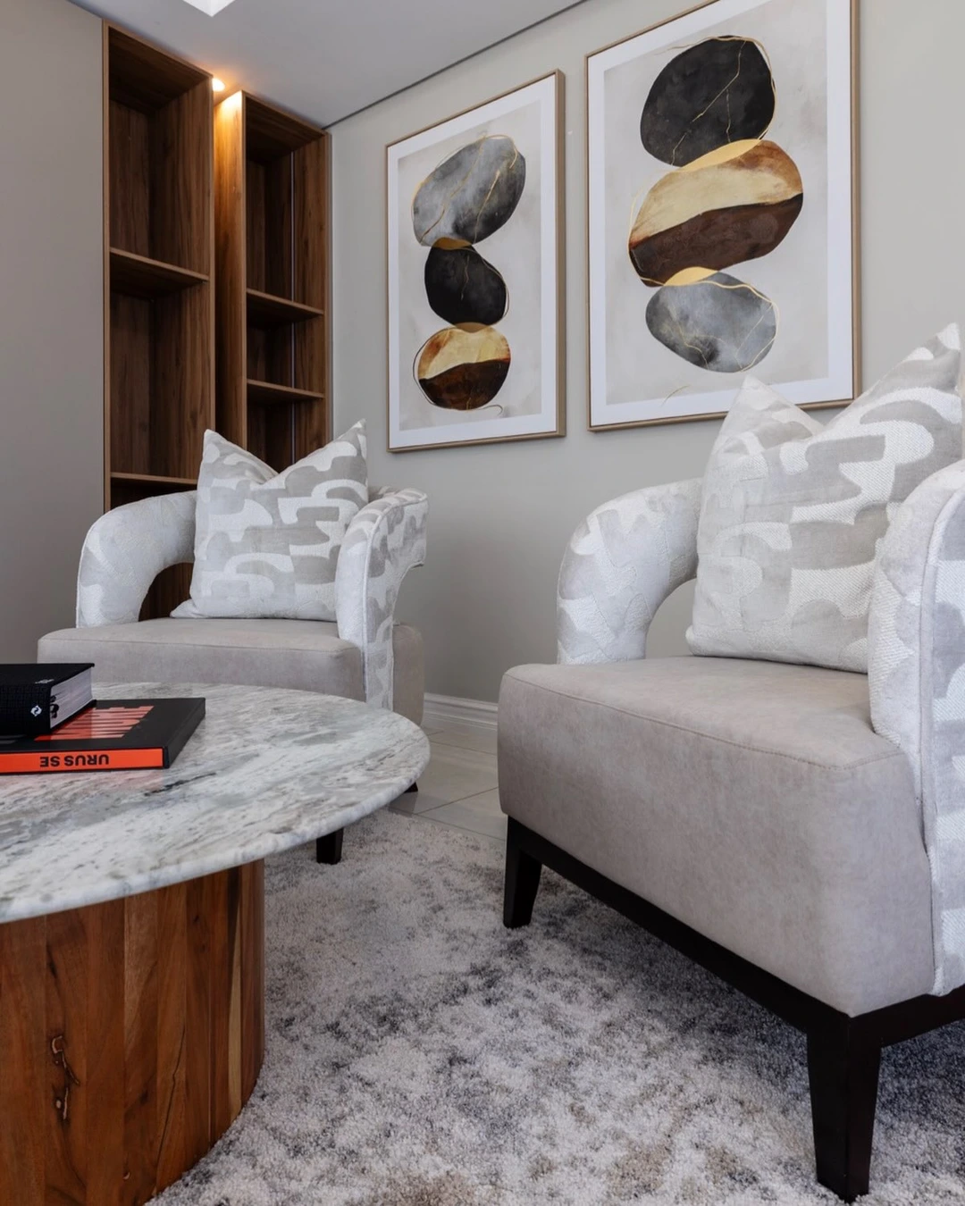 Two matching armchairs with patterned cushions facing each other across a round marble coffee table