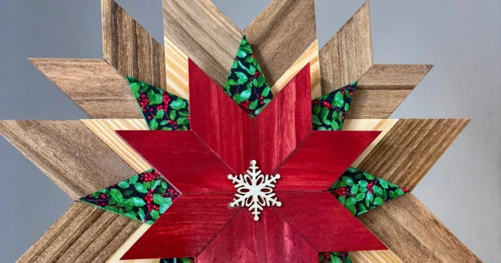 Close-up of a layered wooden, holly-fabric, and red star tree topper with a white snowflake center, outer points trimmed by the landscape crop.