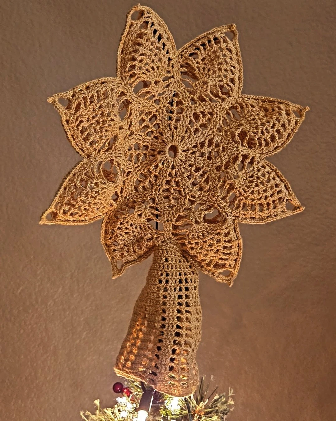 Golden crocheted angel tree topper with an open lace pattern and star-shaped halo