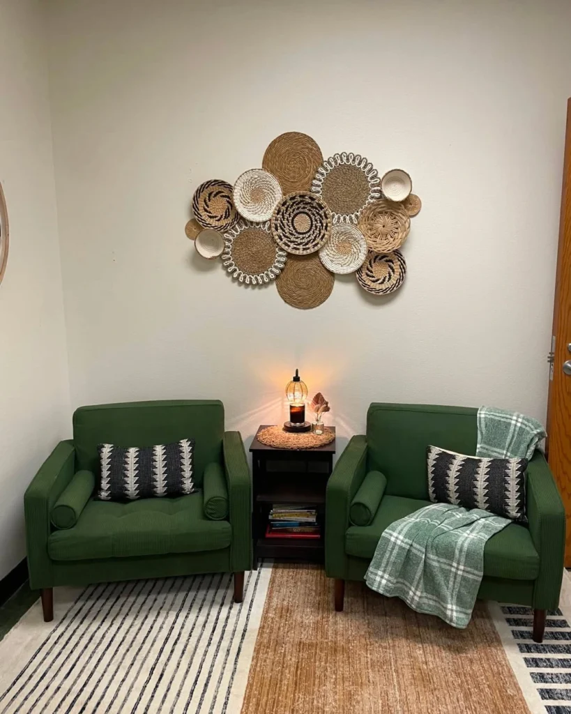 Cluster of woven baskets on a white wall above two green armchairs with patterned pillows