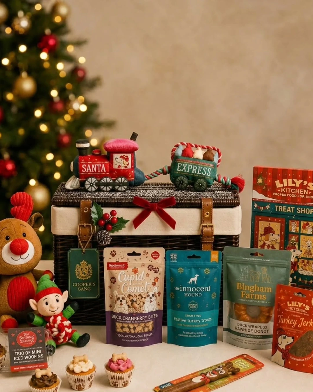 Dog hamper with a Santa Express train toy, reindeer and elf toys, treat bags, mini cupcakes, and an advent calendar at the side.