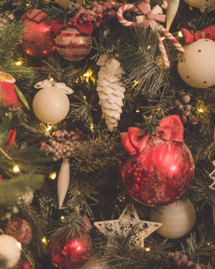 Christmas tree branches decorated with red and white baubles, a white pinecone ornament, candy canes, berries, and a white star.