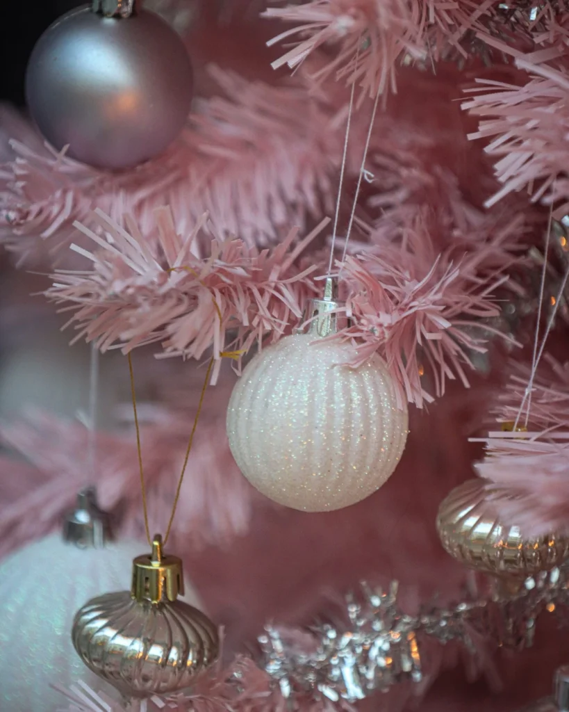 Pink Christmas tree branches with silver, white glitter, and gold baubles and silver tinsel.