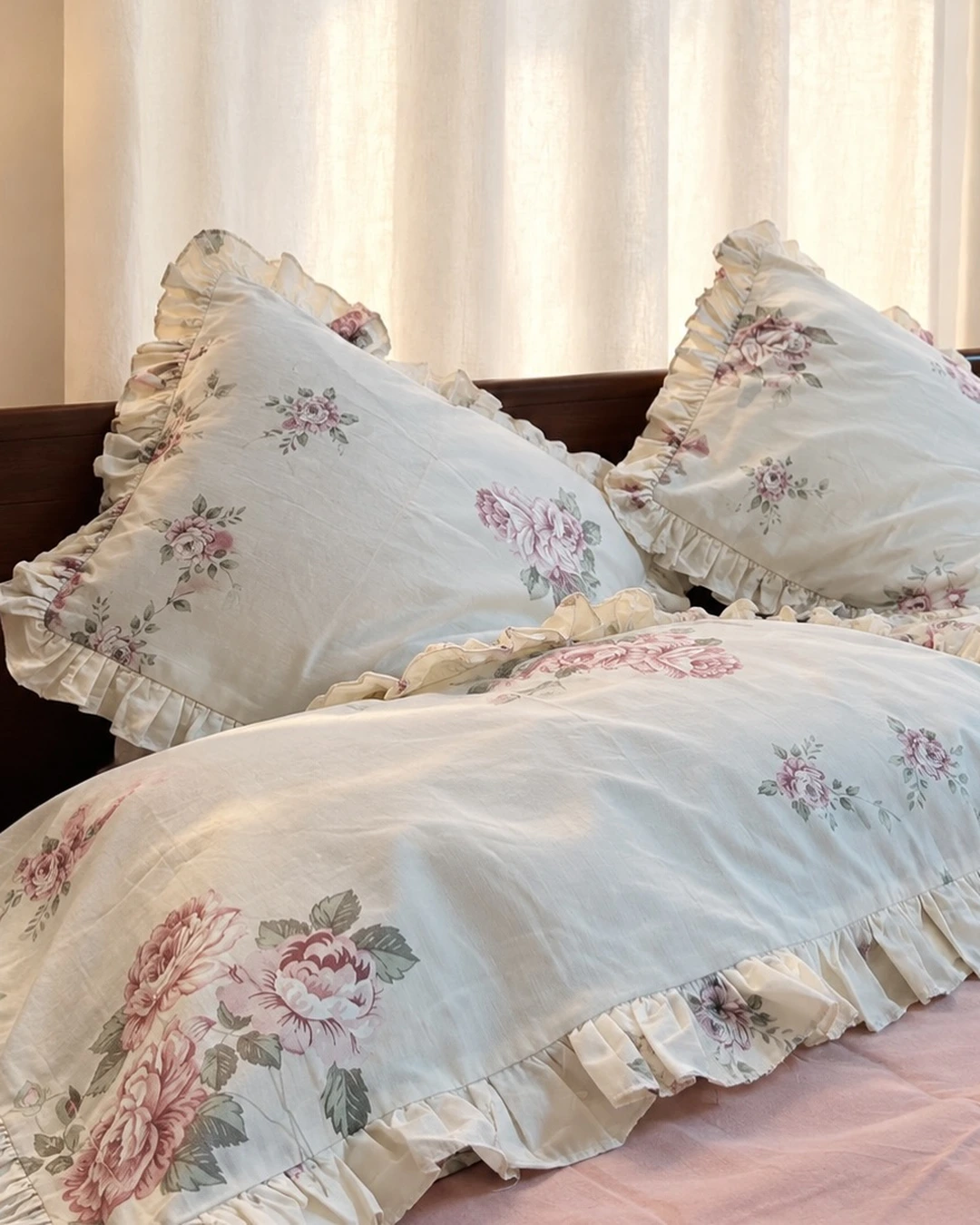 Cream bedding with pink rose prints and ruffled trim on the duvet and pillowcases