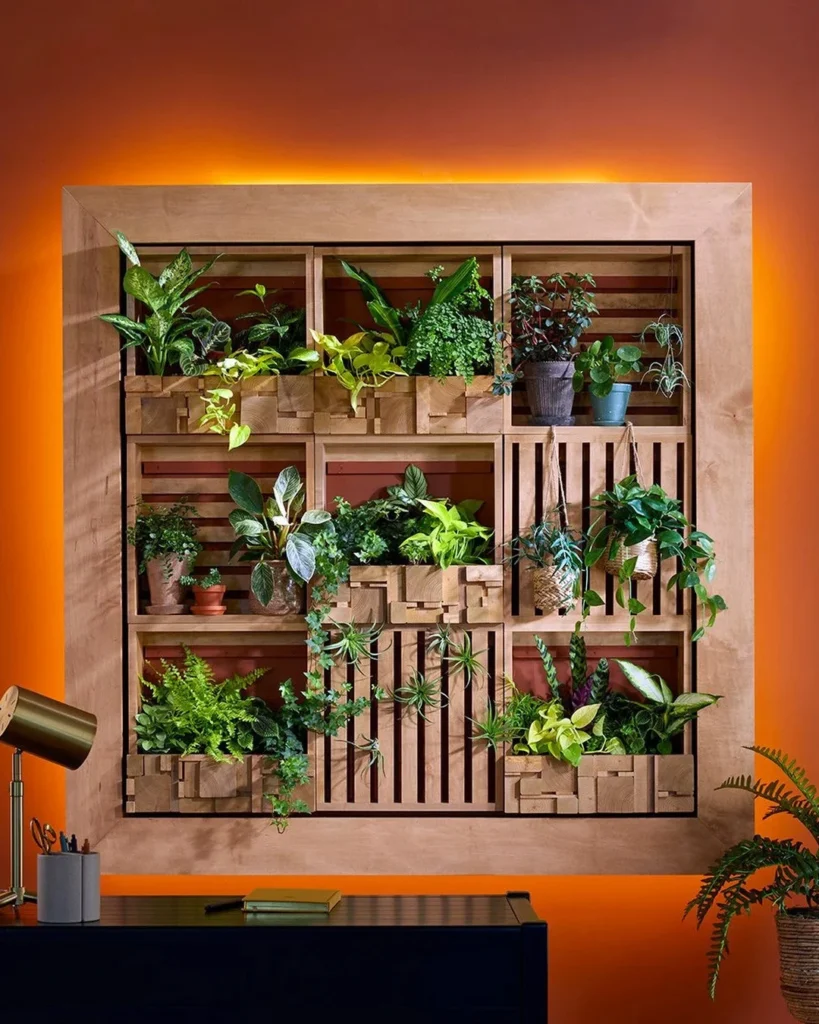 Wooden framed living wall with nine compartments of pothos, ferns, and philodendrons on a bold orange-red wall