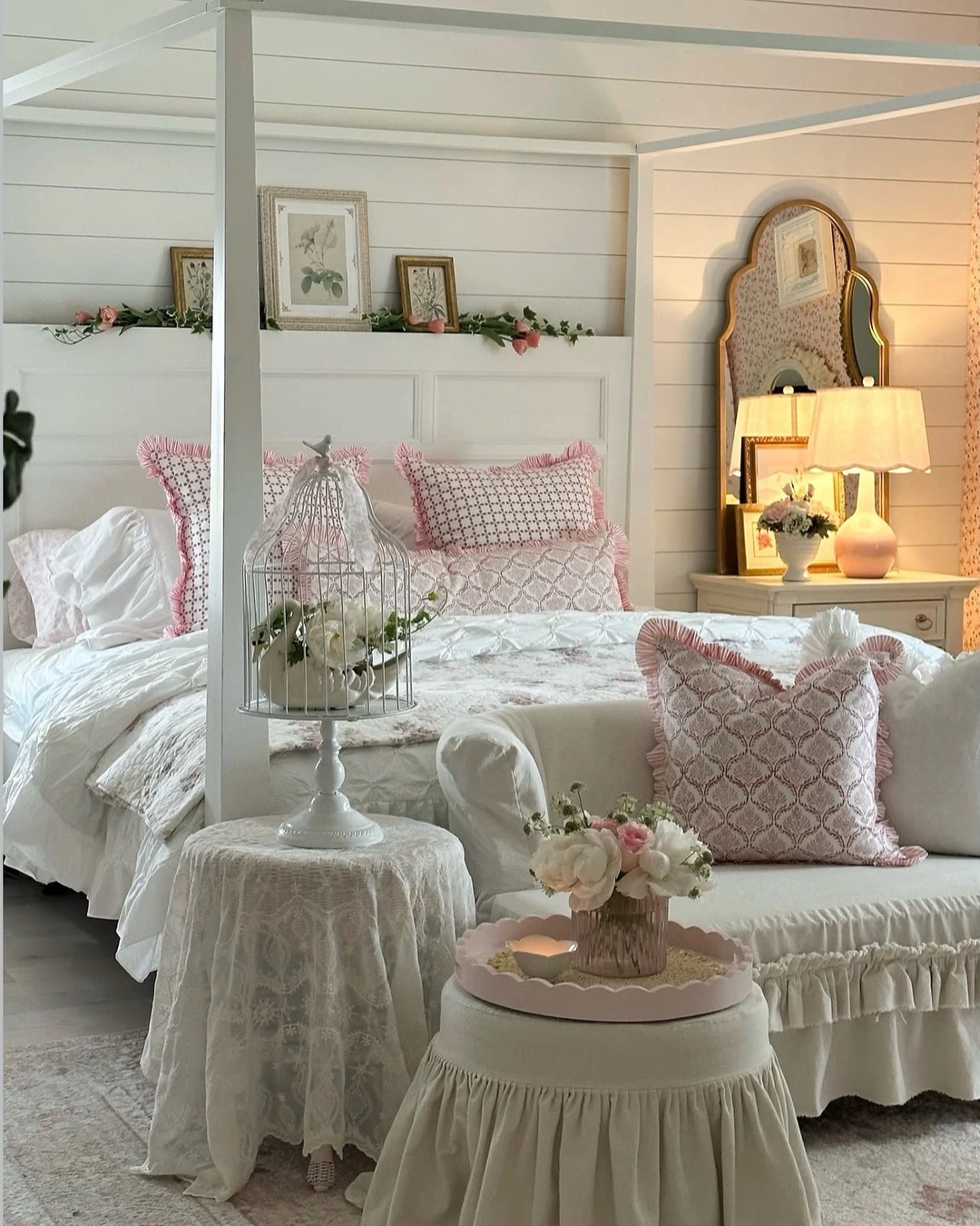 White four-poster bed with pink-patterned pillows with pink ruffle trim in a cottage bedroom
